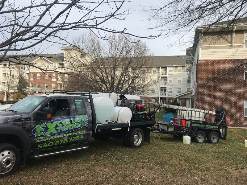 Two service company trucks of Excellent Exterior LLC are in a residential building located in Fredericksburg.